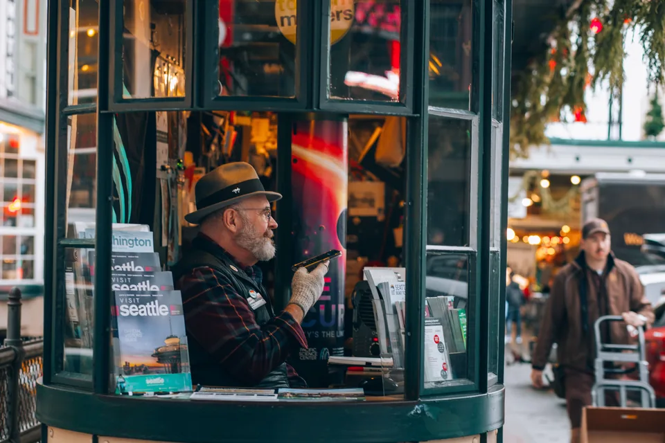 Un conseiller dans un kiosque d'information touristique, entouré de guides et de dépliants pour les visiteurs.
